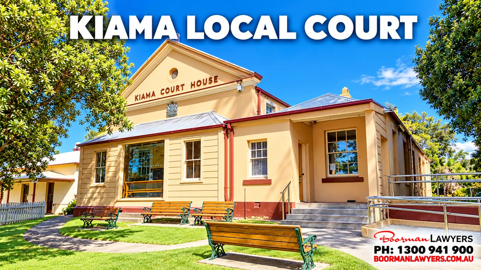 Kiama Local Court, a cream two-storey building with 'Kiama Court House' on the gable and timber benches on the lawn, with the Boorman Lawyers logo and phone number 1300 941 900